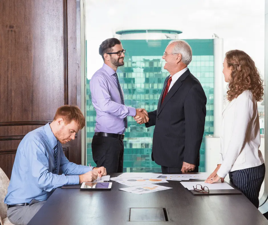 Business professionals shaking hands in a meeting room during lawyer mediation services.