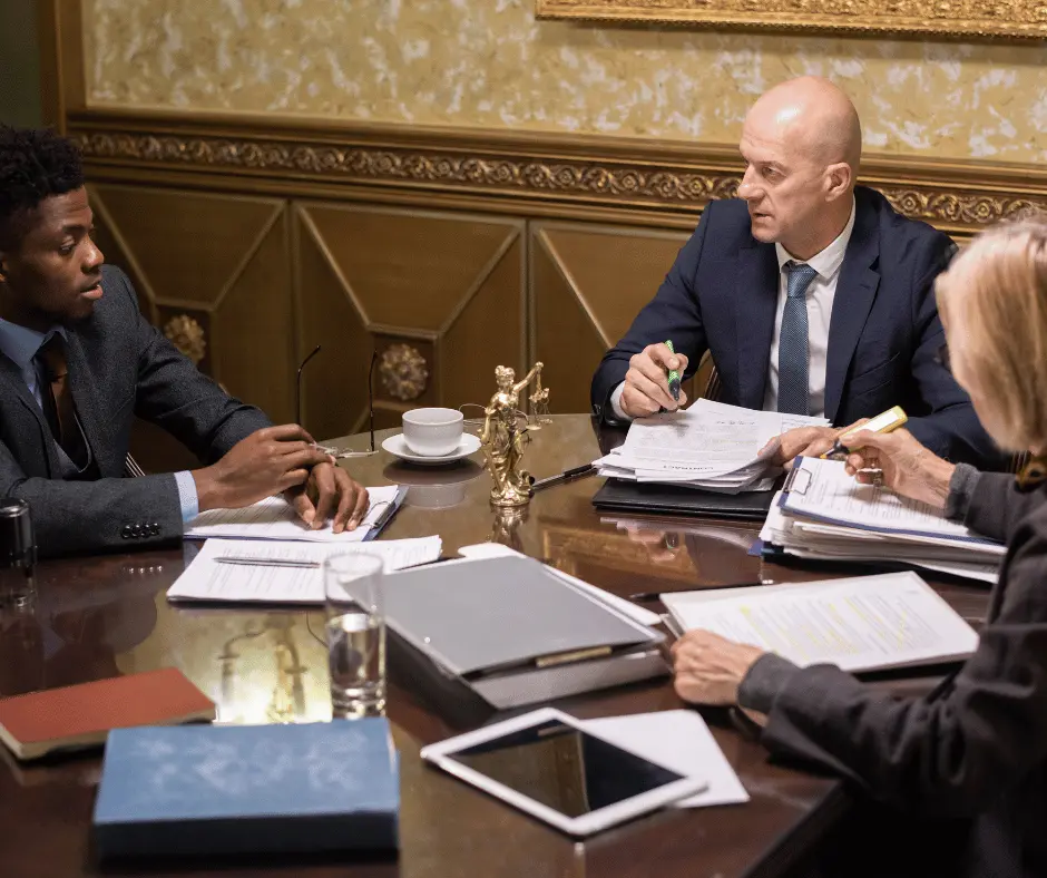 A fajloun legal lawyer engages in legal mediation at a table with two other individuals, discussing important matters.