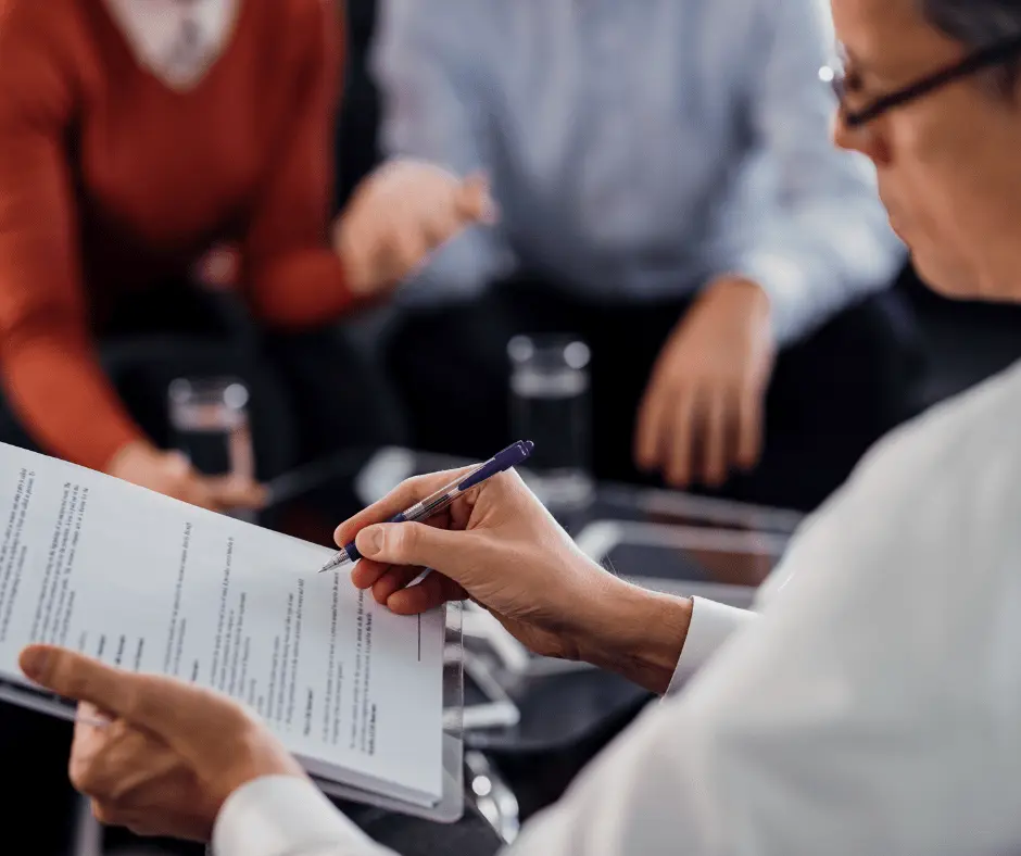 A man is engaged in signing a document, accompanied by two others, highlighting fajloun legal wills and estates services.